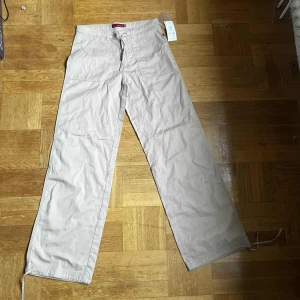 Beige vida byxor med snörning - Beiga byxor från OLÉ i bomull med vida ben och snörning i midjan. De har stora fickor fram och bak, samt dragsko vid benslut.🩷            