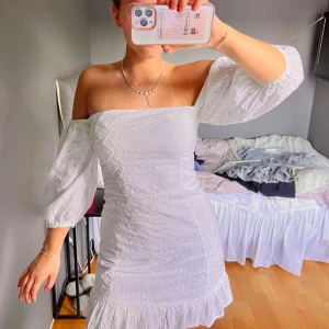 Vit offshoulder klänning - Säljer en söt vit offshoulder klänning med trekvartsärm och volangdetaljer. Perfekt som student klänning!!!🥳