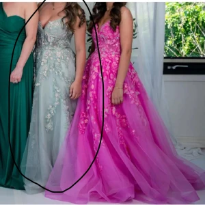 Grön balklänning med blommor - Elegant grön balklänning med blommiga detaljer och glittrande paljetter. Klänningen har en axelbandslös design och en lång, svepande kjol som ger en prinsessliknande känsla. Den är använd en gång samma modell som den rosa fast en annan färg köp direkt för 3000 annars kom med bud❤️storlek 36 och är 163cm man kan korta ner den samt göra den längre då jag sytt upp den köpt för 5500