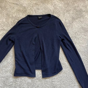 Mörkblå kofta från Gina Tricot - Säljer en stilren mörkblå kofta från Gina Tricot. Den har en enkel knapp framtill och är tillverkad i ett mjukt material. Perfekt för lager-på-lager under kyligare dagar, är i M men skulle säga att den passar S också!💕