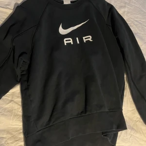 Svart sweatshirt från Nike - Säljer en svart sweatshirt från Nike med det klassiska Air-logotypen i vitt på framsidan. Tröjan har långa ärmar och en rund halsringning. Perfekt för en sportig och avslappnad stil.