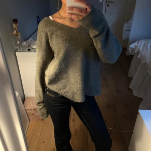 Grå stickad tröja - Mysig grå stickad tröja med v-ringning och långa ärmar. Perfekt för kyligare dagar och enkel att matcha med olika outfits. Lite nopprig men annars bra skick!