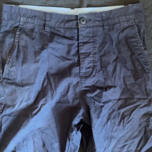 Mörkblå chinos shorts  - Snygga mörkblå chinos med normal passform. Byxorna har en klassisk design med knappar och bälteshällor. Perfekta för en stilren look.