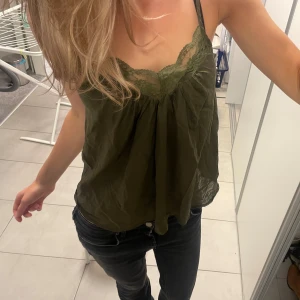 Olivgrön linne med spetsdetaljer - Snygg olivgrön linne med spetsdetaljer vid halsringningen. Från custommade! 