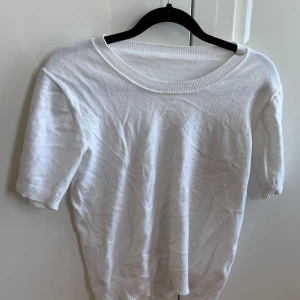 Vit kortärmad tröja - Säljer en enkel vit tröja med korta ärmar. Perfekt för en avslappnad look. Tröjan har en rund halsringning och är tillverkad i ett mjukt material.