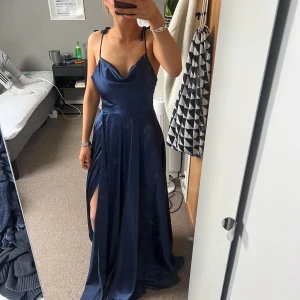 Marinblå balklänning med slits - säljer min fina balklänning från nian som jag inte kommer använda igen då jag ska köpa ny klänning till studenten. Jag är 163 och klänningen är väldigt lång på mig, därmed har den defekter allra längst ner på klänningen. För dig som är 163 och kortare så går det att sy upp den hos skräddare och då kommer defekterna försvinna! Köptes för 1500 kronor och använts under en kväll. För frågor är det bara att skriva! Den är från butiken ”Jolie Bridal” i Malmö!