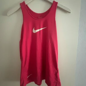 Rosa träningstopp från Nike - Säljer en snygg rosa träningstopp från Nike med det klassiska logotyptrycket på framsidan. Perfekt för träning eller en avslappnad dag. Toppen är ärmlös och har en bekväm passform.