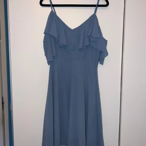 Blå klänning från Lyckliga jag - Snygg blå klänning från Sisters Point (Lyckliga jag)  med volangdetaljer och smala axelband. Klänningen har en dragkedja i ryggen och en luftig passform som ger en elegant look. Det är i storlek XS (kostade 800kr ny och endast använd 1 gång)