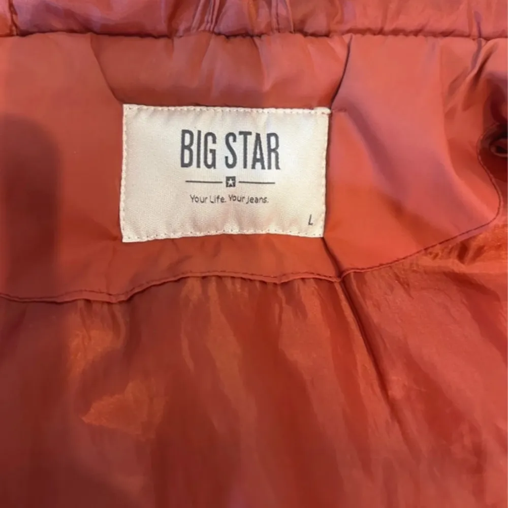Säljer en snygg Röd dunväst från Big Star med dragkedja och huva. Västen har praktiska fickor med knappar och är perfekt för kyligare dagar. Den är quiltad för extra värme och stil. Perfekt för dig som vill hålla stilen i höst och vår.. Takit.