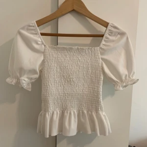 Vit blus med puffärmar - Vit blus med puffiga kortärmar. Köpt utomlands. Endast använd en gång då det inte är min stil. I storlek M men passar mig som har XS-S. För frågor eller fler bilder är det bara och skriva till mig 🥰