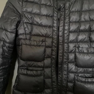 Svart Moncler - Säljer en stilren svart dunjacka från Moncler. Jackan har en quiltad design med dragkedja framtill. Perfekt för kyligare dagar med sin varma och lätta konstruktion. Varm, men ruin och lätt att vara med sig. Jackan är i samma skick som när jag köpt en den och därmed väldigt bra kvalitet.