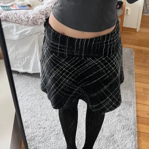 Svart rutig kjol - Snygg svart kjol med vitt rutmönster. Kjolen är perfekt med att matcha med någon liten topp eller klackar. 