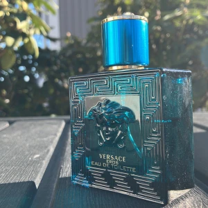 Versace Eros Eau de Toilette - Säljer en flaska Versace Eros Eau de Toilette. Flaskan är i en djupblå färg med ett elegant mönster och en Medusa-logotyp på framsidan. Korken är också blå med gulddetaljer. Perfekt för den som vill ha en doft med stil och karaktär. Har använt ungefär 15 ml av 50