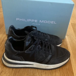 Svarta sneakers från Philippe Model - Säljer mina svarta sneakers ifrån phillipe model, jag köpte dom nya för 3200 från deras hemsida i slutet av november, men använder dom inte längre, skicket är helt okej dom är väldigt smutsiga så ifall man fräschar upp dom lite så är de nog inga problem dom har gått sönder lite på kanten kom privat för bild. Dustbag har jag också och kvitto på telefon. Pris kan diskuteras!!!