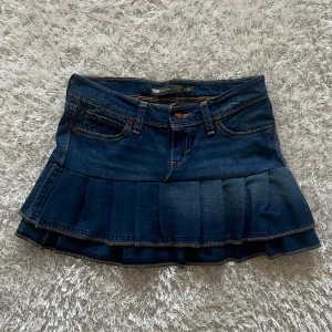 Jeanskjol med volang - En lågmidjad jeanskjol omsydd från ett par jeans Midjemått tvärsöver - 36 cm Längd - 32cm