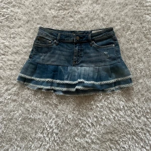Jeanskjol med spetsdetaljer - En lågmidjad jeanskjol omsydd från ett par jeans Midjemått tvärsöver - 35 cm Längd - 27 cm