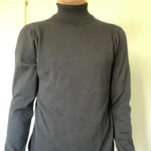 Svart polotröja från H&M - Säljer en klassisk svart polotröja från H&M i storlek M. Tröjan har lång ärm och hög polokrage, perfekt för lager-på-lager eller som den är. Materialet känns mjukt och följsamt mot kroppen.