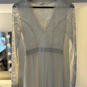 Vit långklänning med spets och v-ringning - Vit långärmad klänningen med spets. Passar perfekt till student eller liknande.