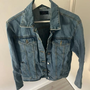 Blå jeansjacka med slitningar - Säljer en klassisk blå jeansjacka från Nelly med slitningar på på båda armarna. Perfekt för dig som gillar en avslappnad och trendig stil.💗