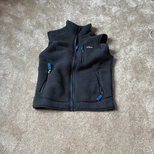 Blå fleeceväst från Patagonia - Säljer en blå fleeceväst från Patagonia i storlek XS. Västen har dragkedja framtill och två praktiska fickor med dragkedjor. Perfekt för lager-på-lager under kyliga dagar. Den är i bra skick förutom att den är lite nopprig. 