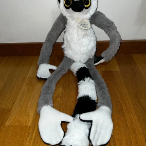 Gosedjur lemur med långa armar - Säljer ett mjukt och fluffigt gosedjur i form av en lemur från Wild Republic. Lemuren har grå och vit päls, stora gula ögon och svart-vit randig svans. Armarna är extra långa och har kardborreband så de kan fästas ihop. Helt ny och oanvänd. 