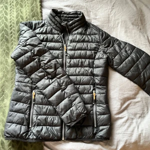 Svart dunjacka från Tuxer - Säljer en svart, lätt och quiltad dunjacka från Tuxer i storlek S. Jackan har hög krage, två dragkedjeförsedda fickor och smidig passform. (Nypris 799kr)