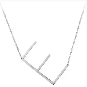Silverfärgat halsband med bokstavsberlock - Stilrent halsband i silverfärg med en stor, geometrisk berlock formad som bokstaven E. Kedjan är tunn och elegant, perfekt för att ge en personlig touch till din stil. INTE RIKTIGT SILVER!