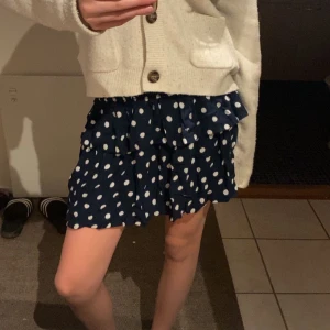  Helt ny Mörkblå prickig volangkjol - Supersöt mörkblå kjol med vita prickar och volangdetaljer. Kjolen har en kort längd och en flowy passform som ger en lekfull känsla. Perfekt att styla med en stickad tröja eller en enkel topp. Lapp sitter kvar 😁