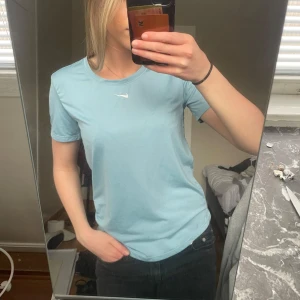 Ljusblå Nike t-shirttt - Säljer en ljusblå Nike Dri-FIT t-shirt med rund hals och ett Nike märke på bröstet. T-shirten är tillverkad i ett mjukt och funktionellt syntetmaterial som andas, perfekt för träning. Klassisk passform och korta ärmar.