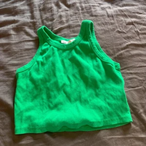 Grön croppad linnetopp - Säljer en grön croppad linnetopp med rund halsringning. Perfekt för varma dagar och enkel att matcha med jeans eller kjol.