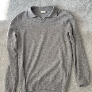Grå stickad polotröja från John Henric - Säljer en klassisk grå stickad polotröja från John Henric. Tröjan har lång ärm, krage och v-ringning. Perfekt för lager-på-lager och passar till många olika stilar.