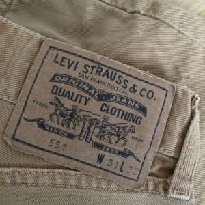 Beiga Levis 551 jeans - Säljer ett par klassiska beiga Levis 551 jeans med rak passform. Byxorna har fem fickor, dragkedja och knapp i midjan samt Levis-logga på bakfickan. Perfekta för en avslappnad och stilren look. Fint skick 