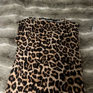 Leopardmönstrad topp från Black Label Collection - Cool leopardmönstrad topp från Black Label Collection i storlek S. Toppen har ett klassiskt snitt med rund hals och ärmlös design. Perfekt för dig som vill sticka ut med ett djurmönster.