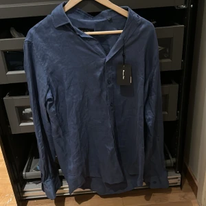 Blå linneskjorta från Massimo Dutti - Snygg blå skjorta i 100% linne från Massimo Dutti. Skjortan har klassisk krage, knäppning framtill och långa ärmar. Perfekt för en stilren och avslappnad look. Aldrig använd. 