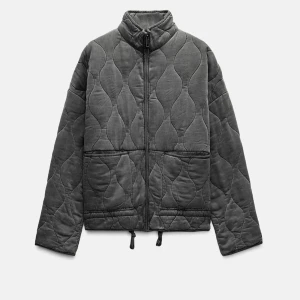 Grå quiltad Zara jacka med dragkedja - Säljer en grå quiltad jacka med dragkedja framtill och hög krage. Jackan har långa ärmar och dragsko nertill för justerbar passform. Perfekt för kyligare dagar och enkel att matcha med olika outfits.