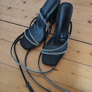 Svarta sneakers med vita detaljer och klack sandaler - Säljer ett par svarta buggati  sneakers med vita och grå detaljer. Skorna har snörning och en grov sula som ger bra grepp. Ovandelen är i mesh och syntetmaterial, vilket gör dem både lätta och luftiga. Perfekta för vardagsbruk eller en aktiv dag. Och en sandaler.