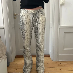 Ormmönstrade GUESS jeans - Säljer ett par snygga byxor med ormmönster i grått och beige. Kommer från GUESS. Raka i modellen och i bra skick! 