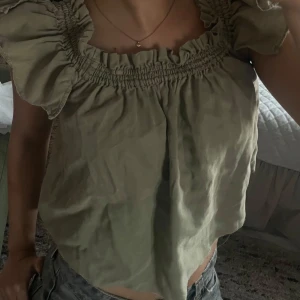 Grön blus med volang - Lljusgrön blus med bred resår och volangdetaljer vid halsringningen och ärmarna. 