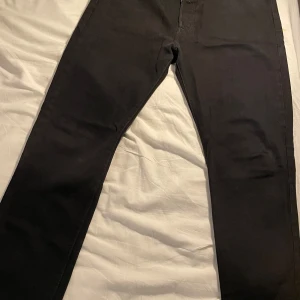 Svarta Levi's 501 jeans W36 L32 - Säljer ett par klassiska svarta Levi's 501 jeans med raka ben och normal passform. Jeansen har fem fickor, knappgylf och den ikoniska läderpatchen bak i midjan. Perfekta för dig som gillar tidlös stil och vill ha ett par jeans som funkar till allt.