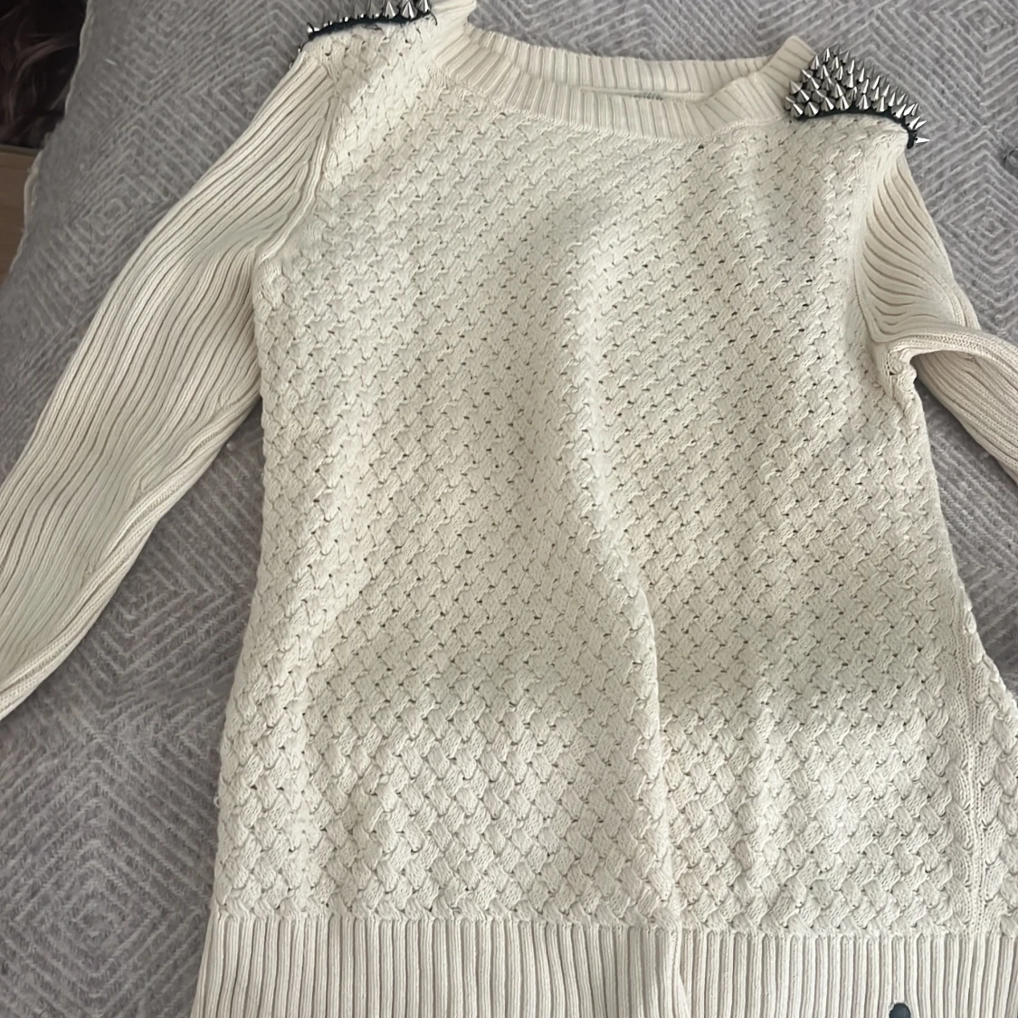 Vit stickad tröja med nitar på axlarna