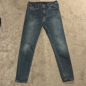 Tiger of sweden jeans Evolve - Säljer ett par blå tiger of sweden jeansbyxor, modell Evolve. Jeansen har fram och bakfickor fickor, raka ben och normal passform. De har snygga slitningar framtill för en trendig look.