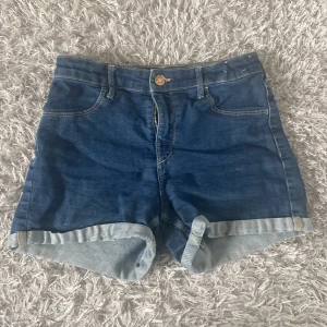 Blå jeansshorts  - Snygga blå jeansshorts från hm med klassisk fyrficksdesign och uppvikta benslut. Perfekta för varma dagar och enkla att matcha med olika toppar. Stängs med dragkedja och knapp framtill.