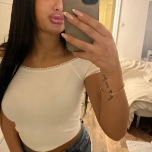 Vit croppad topp med spetskant - Säljer en vit croppad topp med rund halsringning och fin spetskant. Toppen har korta ärmar och sitter tight. Perfekt att matcha med jeans eller kjol.