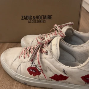 Zadig voltaire skor  - Vita sneakers med röda hjärtan på sidan och snören med röd text. Skorna är ifrån Zadig, box och påse följer med när man köper skorna💕skriv om ni har några frågor! Priset är diskuterbart, bara att höra av er!💕Dom är stolek 41 men skulle säga att de både passar 40-41💕kan tänka mig sälja dom för lägst 1000!!