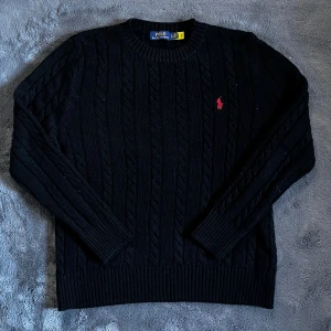 Ralph Lauren kabelstickad  - Säljer en helt ny kabelstickad svart tröja från Polo Ralph Lauren med rund halsringning och röd broderad logga på bröstet. Storlek XL men passar M/L. Skick 10/10. Pris går att diskutera✅