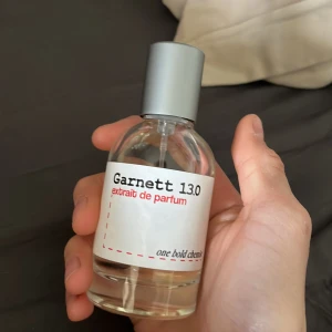 Garnett 13.0 Extrait de Parfum - En stilren parfymflaska med transparent glas och silverfärgad kork. Märkt med Garnett 13.0 extrait de parfum från one bold chemist. Modern och minimalistisk design, perfekt för dig som gillar unika dofter.