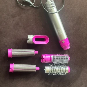 5 i 1  Airwrap multistyler  - Säljer en 5 i 1 Airwrap multistyler i silver och rosa med flera utbytbara tillbehör: två locktillbehör, två rundborstar och en fönmunstycke. Perfekt för att styla och forma håret med olika effekter. Snygg design och enkel att använda. Knappt använd, 1000watt och nypris 699kr