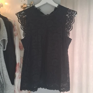 Svart spetsblus från Pieces - Säljer en svart ärmlös spetsblus från Pieces i storlek S. Blusen har fina virkade spetsdetaljer längs ärmhålen och halsen. Knappt använd och är i fint skick!💓