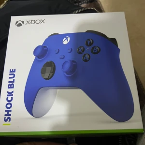 Xbox  kontroll  - Säljer en original Xbox thandkontroll i färgen  Blå. Kontrollen har en matt blå framsida, svarta knappar och detaljer samt vit baksida. Passar Xbox Series X/S och PC. Perfekt för gaming och har ergonomisk design.