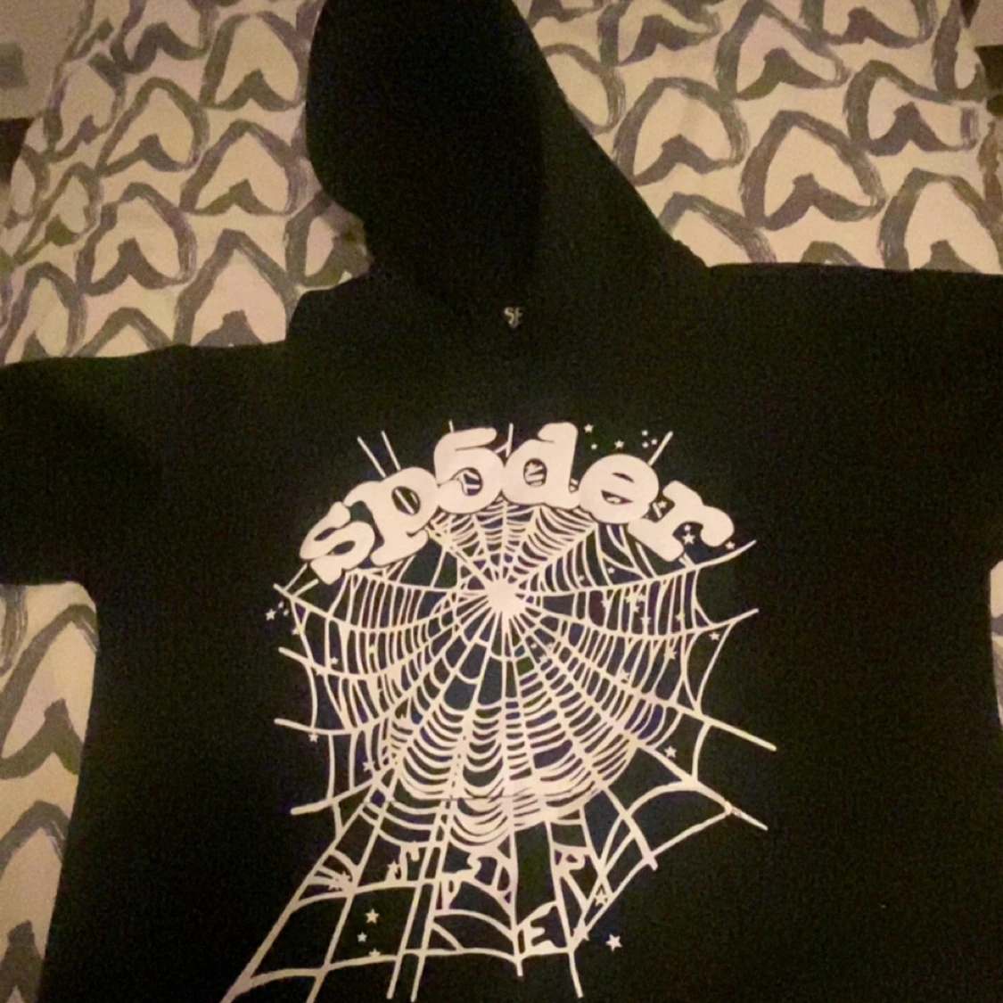 Svart hoodie med spindelnätsmotiv från SP5DER